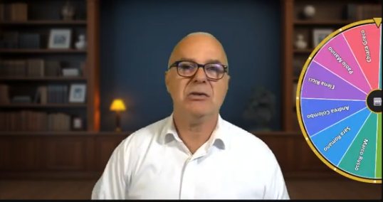 Federico in camera; accanto, la ruota con i nomi dei partecipanti sceglie chi prende la parola